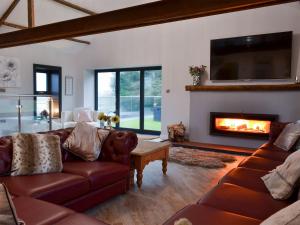 a living room with leather couches and a fireplace at North Plain Barn in Bowness-on-Solway