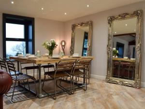 a dining room with a table and mirrors at North Plain Barn in Bowness-on-Solway