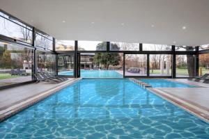 a large swimming pool with blue water and windows at Premier Resort Sani Pass in Himeville