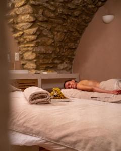 un hombre acostado en una cama en una habitación en Le Moulin de Vernègues Hôtel & Spa, en Mallemort