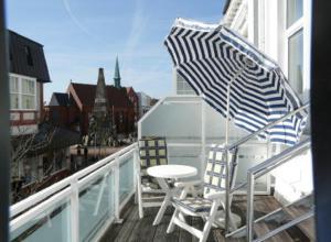 a chair and an umbrella sitting on a balcony at Haus Meeresbrise Haus Karin in Norderney