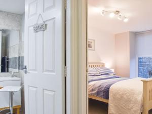 1 dormitorio con 1 cama y puerta con lavamanos en Millys Cottage, en Ayton