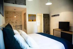 a bedroom with a large white bed and a television at LA PETITE MAISON DE MAUSSANE *** in Maussane-les-Alpilles