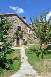 una casa de piedra con un árbol delante en Casa Rural La Casa de Piedra, en Navarredonda de Gredos