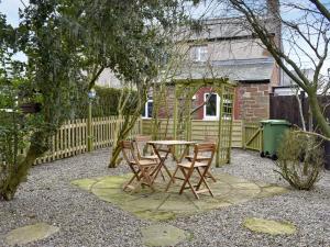 d'une terrasse avec une table, des chaises et une clôture. dans l'établissement Toms Cottage, à Melmerby