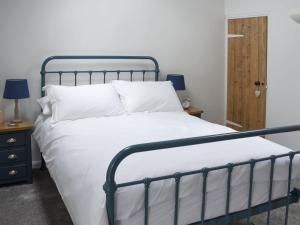 Una cama con sábanas blancas y almohadas en un dormitorio en Toms Cottage en Melmerby