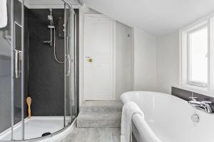 a white bathroom with a tub and a shower at 1 Quayside in Appledore +40 photos