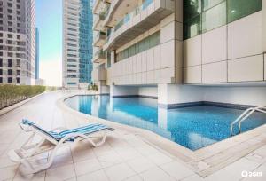 uma piscina do hotel com uma cadeira e um edifício em Dream Inn Apartments - Marina Pinnacle em Dubai
