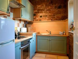 a kitchen with blue cabinets and a brick wall at The Coach House - UK30397 in Calvo