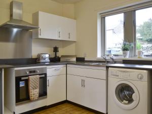 uma cozinha com armários brancos e uma máquina de lavar e secar roupa em Ribblestones em Austwick