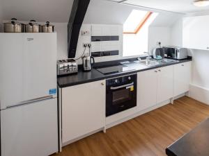 a kitchen with white cabinets and a black stove top oven at The Coach House Apartment in Edwinstowe