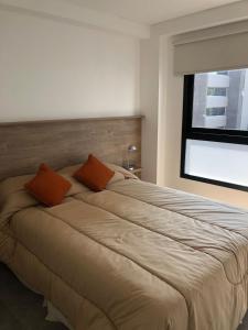 sypialnia z dużym łóżkiem z 2 pomarańczowymi poduszkami w obiekcie Departamento para 3 con parrilla privada y PILETA! w mieście Salta