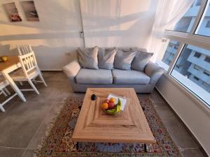 uma sala de estar com um sofá e uma tigela de fruta numa mesa em Beautiful 2-Bedroom Sea-View apartment em Netanya