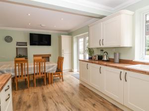 a kitchen with white cabinets and a dining room with a table at Highbank in Wareham