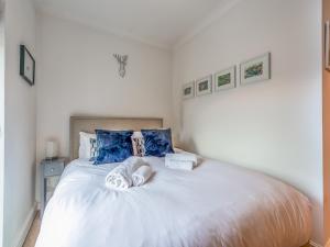 una camera da letto con un grande letto bianco con cuscini blu di Pass the Keys Balham Modern Cosy Apartment a Londra