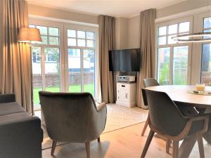 uma sala de estar com uma mesa e cadeiras e uma televisão em Ferienwohnung Strandmuschel em Wangerooge