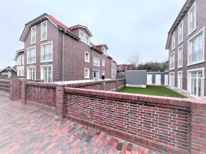 eine Backsteinmauer vor einigen Gebäuden in der Unterkunft Ferienwohnung Strandmuschel in Wangerooge