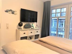 um quarto com uma televisão de ecrã plano numa cómoda branca em Ferienwohnung Inselherz em Wangerooge