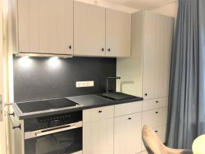 uma cozinha com armários brancos e um forno com placa de fogão em Ferienwohnung Inselherz em Wangerooge