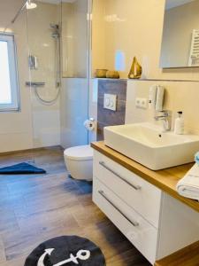 a bathroom with a sink and a toilet and a shower at Dünenhaus Ferienwohnung De Düün Dree in Wangerooge +10 photos