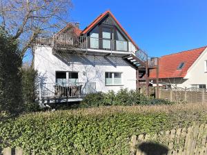 a white house with a balcony on top of it at Dünenhaus Ferienwohnung De Düün Dree in Wangerooge