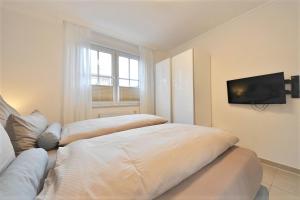 een slaapkamer met 2 bedden en een tv aan de muur bij Villa Vivaldi - Ferienwohnung 3 in Wangerooge