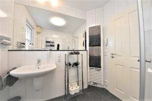 een witte badkamer met een wastafel en een spiegel bij Villa Vivaldi - Ferienwohnung 3 in Wangerooge