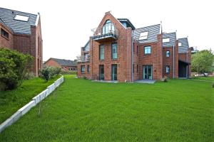 a large brick building with a green lawn in front of it at Ferienwohnung Strandbude in Wangerooge