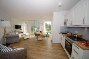 a kitchen and living room with white cabinets and a table at Ferienwohnung Strandbude in Wangerooge