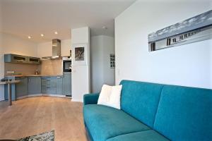 a living room with a blue couch and a kitchen at Ferienwohnung Dünenperle in Wangerooge +6 photos