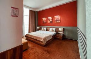 Avenue Hotel Baku by Smart في باكو: غرفة نوم بسرير وجدار احمر