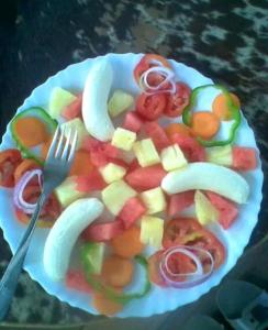 a plate of fruit and vegetables with a fork at Lake Lyantonde eco campsite original in Fort Portal