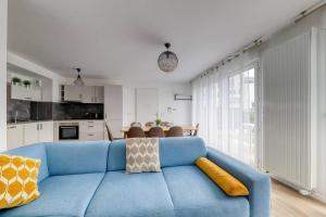 a living room with a blue couch and a kitchen at Le duplex Disneyland Bmyguest in Montévrain