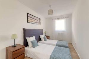 a white bedroom with two beds and a window at Le duplex Disneyland Bmyguest in Montévrain