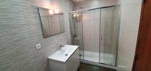ein weißes Badezimmer mit Waschbecken und Dusche in der Unterkunft Casa Rosa in Monte Gordo