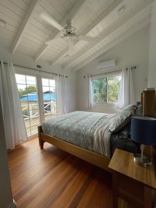 a bedroom with a bed and a table and windows at Sound of The Sea-walking distance to everything in Placencia Village
