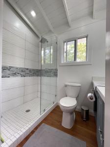 a white bathroom with a shower and a toilet at Sound of The Sea-walking distance to everything in Placencia