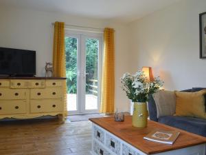 sala de estar con sofá y mesa con flores en Blaithwaite Cottage, en Blencogo