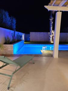 Villa Nawel Piscine privée et chauffée sans vis-à-vis في أغادير: مسبح في الليل مع طاولة وكرسي