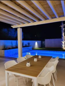 Villa Nawel Piscine privée et chauffée sans vis-à-vis في أغادير: غرفة طعام مع طاولة خشبية وكراسي بيضاء
