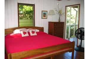 a bedroom with a red bed with two pillows at Seagrape Escape in Maya Beach