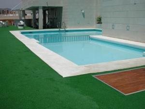 a large swimming pool with green grass next to a building at Hotel Oasis Plaza in Benidorm