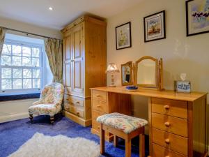 a bedroom with a dresser and a mirror and a chair at Middle Cottage in West Burton