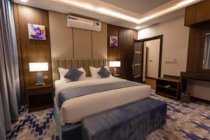 um quarto de hotel com uma cama grande e duas lâmpadas em Aman Hotel Suites em Abha