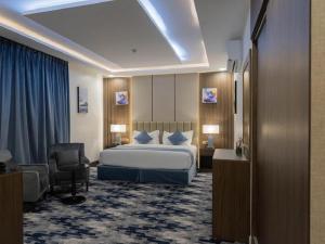 Habitación de hotel con cama y silla en Aman Hotel Suites en Abha