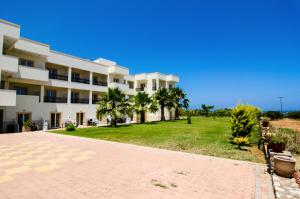 a large apartment building with a lawn and palm trees at Real Palace in Malia
