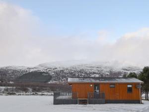 a small cabin in the snow with mountains in the background at The Den in Etteridge