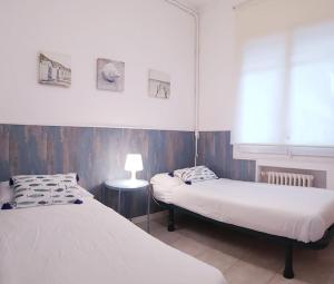 two beds in a room with a lamp on a table at Enjoy your holidays 300m to the Mediterranean sea at Villa DIVALI in Castelldefels