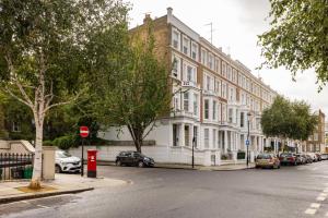 una calle con coches estacionados frente a un edificio en The Kensington And Chelsea Classic - Glamorous 2BDR Flat en Londres