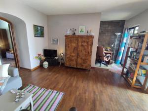een woonkamer met een hardhouten vloer en een kamer met een boekenplank bij Het Boetje in Lagoa